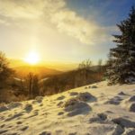 Sun rising above hills covered with snow in winter nature