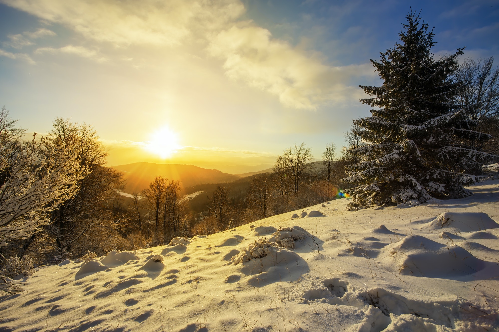 Sun rising above hills covered with snow in winter nature