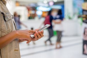 Young woman hand holding typing smartphone to chat at shopping mall.