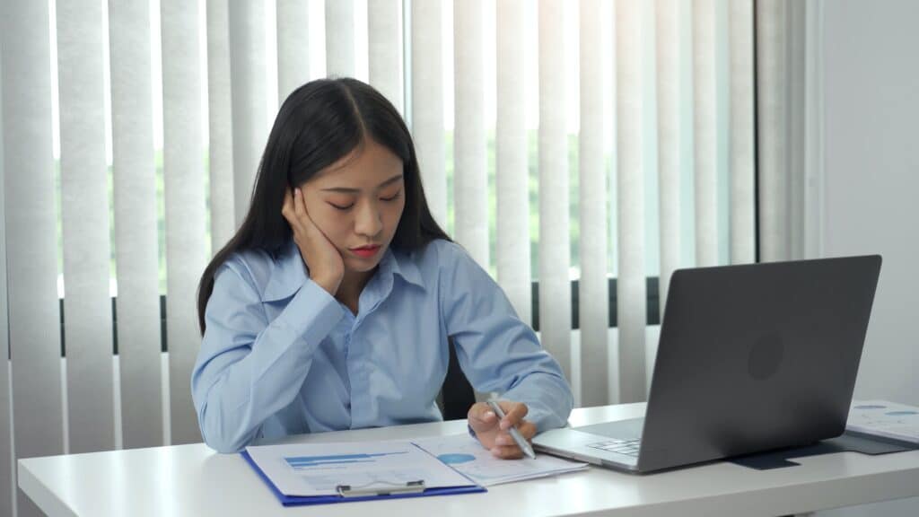 Asian women are bored from working at the office.